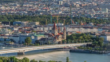 Aerial panoramic view of Vienna city with Church of St. Francis of Assisi, historic buildings and a riverside promenade timelapse in Austria. Evening skyline before sunset from Danube Tower viewpoint clipart