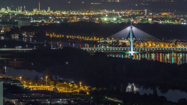Viyana üzerinde gökdelenler, Donaustadt Köprüsü ve Avusturya 'da nehir kenarında bir gece gezintisi olan panoramik bir manzara. Tuna Kulesi perspektifinden aydınlatılmış gökyüzü