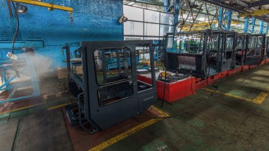 Konveyör montajı, traktörün gövdesini büyük endüstriyel fabrika zaman diliminde sahneleyecek. Birçok işçi tarafından kabin montajı, montaj parçaları