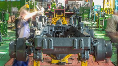 Konveyör montajı, traktörün gövdesini büyük endüstriyel fabrika zaman diliminde sahneleyecek. Çerçeve montajı, Chassis kurulumu ve diğer bölümler etrafındaki işçiler.