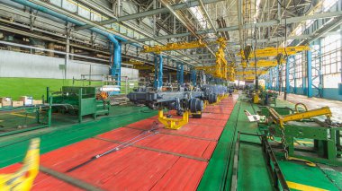 Konveyör montajı, traktörün gövdesini büyük endüstriyel fabrika zaman diliminde sahneleyecek. Çerçeve montajı, montaj parçaları. Arkaplanda çalışma bankları