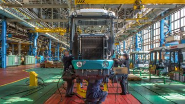 Konveyör montajı, traktörün gövdesini büyük endüstriyel fabrika zaman diliminde sahneleyecek. Çerçeve montajı, radyatör ve kabin kurulumu ve diğer parçaları olan motor.