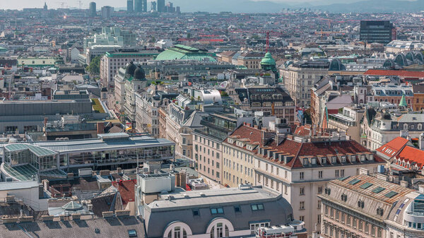 Panoramic aerial view of Vienna, Austria, from south tower of St.. Stephen's cathedral timelapse. City skyline with historic buildings roofs from above at sunny day. Skyscrapers far away