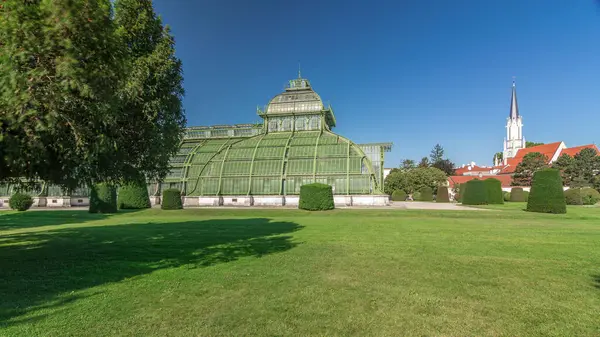 stock image The Palmenhaus Schoenbrunn timelapse hyperlapse - a large greenhouse in the park Schoenbrunn in Vienna, Austria. Green lawn with flowerbed around