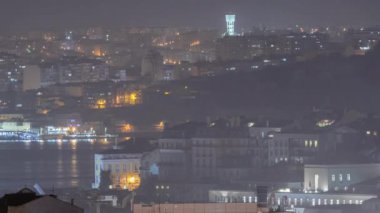 Lisboa 'nın şehir merkezindeki gece görüntüsü. Baixa, Rossio ve Chiado 'nun çatıları yukarıdan panoramik. Aydınlatılmış binalar. Almada, Tejo nehrinin diğer tarafında. Portekiz