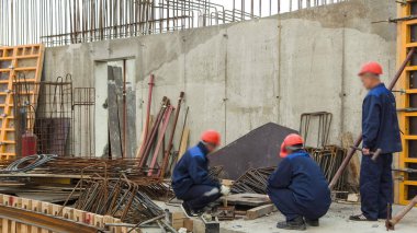 Yarı otomatik kaynak makinesinde çalışan kaynakçılar inşaat alanındaki bir zaman diliminde metal takviyesi yapıyorlar. Üniformalı ve beton işçileri