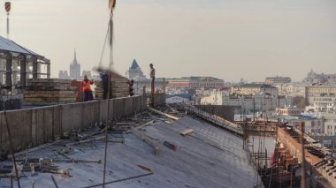 İnşaat alanında beton takviyesi için çelik çubuk inşaat iskeleti takviyesi. Üniformalı birçok işçiyle birlikte yeni binanın çatısına metal plakalar yüklüyorlar.