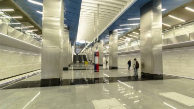 Trenlerin zaman ayarlı olduğu modern bir metro istasyonu. Arka planda yürüyen merdivenler ve merdivenler