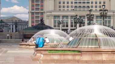 Moskova 'da fıskiyeleri ve bankları olan Manezh Meydanı. Arka planda Moskova Oteli. Cam kubbeler ve sokak lambaları