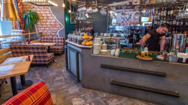Kasası, ahşap masaları ve sandalyeleri olan, insanlardan yoksun modern bir kafenin zaman çizelgesi. Kafede kahve makinesi ve içecek bardakları olan bir çay barı var..
