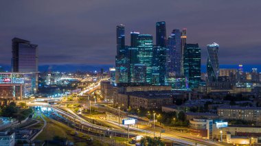 Moskova Uluslararası İş Merkezi 'nin (Moskova-Şehir) şehir trafik zaman çizelgesi ve gökdelenlerinin gece gündüz geçiş görüntüsü. Kievskiy tren istasyonunun yanındaki çatıdan gökyüzü manzarası