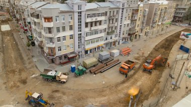 Endüstriyel kazıcı inşaat alanından toprak malzemelerini bir çöp kamyonuna yüklüyor. Tramvay raylarının yeniden inşası. Yukarıdan hava üstü görünümü