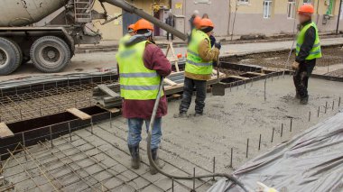 Beton, yol bakım şantiyesinde çok sayıda işçi ve mikser zaman ayarlı çalışıyor. Tramvay raylarının yeniden inşası