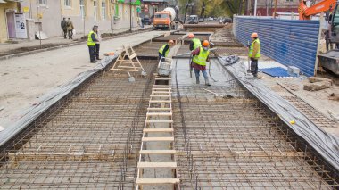 Yol onarım sahasında pek çok işçi ve mikser zamanı olan metal şebekeye beton dökülüyor. Tramvay raylarının yeniden inşası
