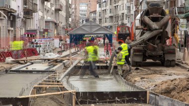 Beton döşeme, yol onarım şantiyesinde birçok işçi ve mikser zaman ayarlarıyla çalışıyor. Tramvay raylarının yeniden inşası