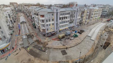 Beton yol yapımında çok sayıda işçi ve mikser makinesi, vinç, traktör zaman ayarlı çalışır. Tramvay raylarının yeniden inşası. Yukarıdan tüm gün boyunca gökyüzü görüntüsü
