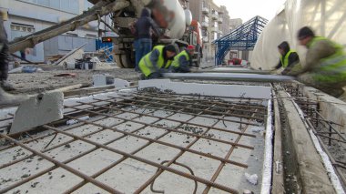 Pouring ready-mixed concrete after placing steel grid reinforcement to make the road by concrete mixer timelapse hyperlapse. Reconstruction of tram tracks on a city street clipart