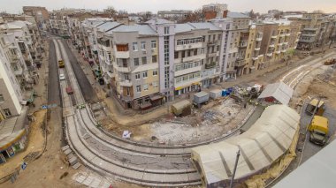 Beton yol onarım şantiyesinde çadır ve mikser altında çalışan birçok işçiyle çalışıyor. Tramvay raylarının yeniden inşası sırasında yeni raylar kurulumu