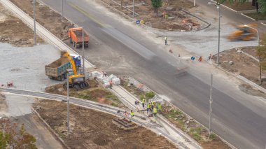 Zemin hareketli ve yol inşaat sitesinde bir damperli kamyon timelapse içine yükleme Endüstriyel Kamyon yükleyici tarak. Tramvay parça yeniden inşası, havadan görünümü