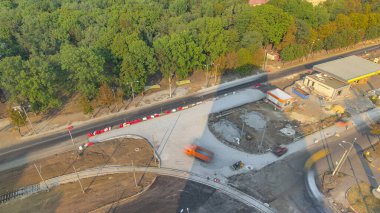 Turuncu titreşimli sıkıştırıcı, yol yapımında ve zaman ayarında ezilmiş taşların üzerinde yuvarlanıyor. Buldozer toprağı hareket ettiriyor ve toprağı kazıyor. Tramvay raylarının yeniden inşası. Havadan üst görünüm