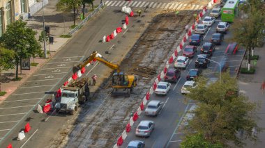 Endüstriyel kamyon yükleyicisi toprağı taşıyor ve eski demiryolu uyuyanlarını yol inşaatındaki bir çöp kamyonuna yüklüyor. Tramvay raylarının yeniden inşasının havadan görüntüsü