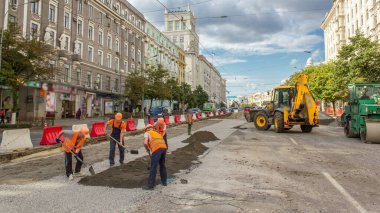 Buldozer taşır ve toprak ve moloz yol timelapse üzerinde yayılır. İşçiler turuncu bir tramvay inşası Tekdüzen izler. Yol yapım aşamasında.