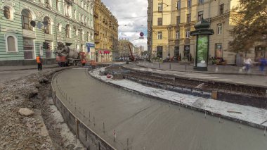 Beton, turuncu üniformalı ve mikser makineli işçilerle yol inşaatı için şehir caddesinde çalışıyor. Tramvay raylarının yeniden inşası