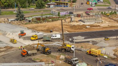 Birkaç endüstriyel makineli zaman ayarlı geniş yol şantiyesinin havadan görüntüsü. Kazı makineleri ve beton levhaları hareket ettiren vinçlerle yer değiştirme ekipmanları.