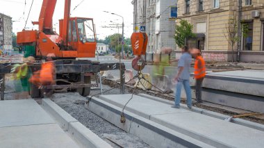 Vinç yol inşaat site timelapse, beton plaka yükleme. Kavganın ve üniforma ile sanayi işçileri. Sokak şehir tramvay yeniden inşası izler