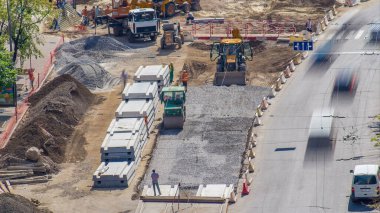 Yeşil titreşimli sıkıştırıcı yol yapımında ve zaman ayarında bir taşın üzerinde yuvarlanıyor. Endüstriyel kazıcı toprağı hareket ettiriyor ve kazıyor. Tramvay raylarının yeniden inşası. Havadan üst görünüm
