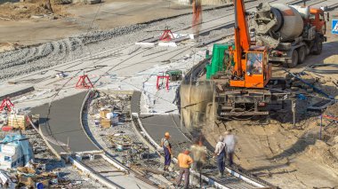 Yol yapımı için vinçten beton dökülüyor. Üniformalı ve mikser makineli bir sürü işçi var. Tramvay raylarının yeniden inşası