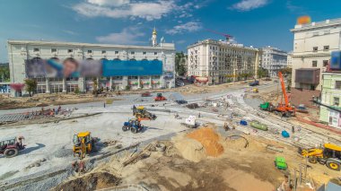 Road construction site with concrete works for road construction with many workers in uniform and many machines with trucks and bulldozers panoramic aerial timelapse. Reconstruction of tram tracks