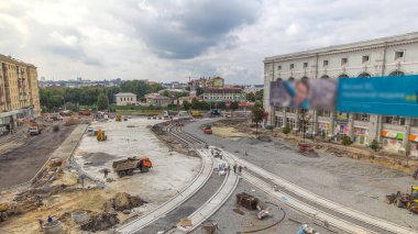 Work trucks and mixers on the construction site of a road timelapse. Crushed stone on substrate. Support activities and industrial machinery. Reconstruction of tram tracks. Aerial top view from above