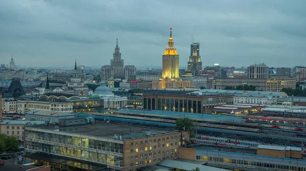 stock image Evening top view of three railway stations day to night transition timelapse at the Komsomolskaya square in Moscow, Russia. Trains on tracks. Stalin skyscrapers on background. Aerial view from rooftop