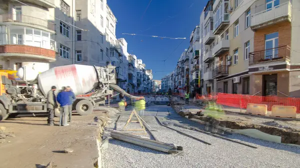 Beton, yol onarım inşaatı için bir moloz yığınında çalışıyor. Bir sürü işçi ve mikser makinası var. Tramvay raylarının yeniden inşası