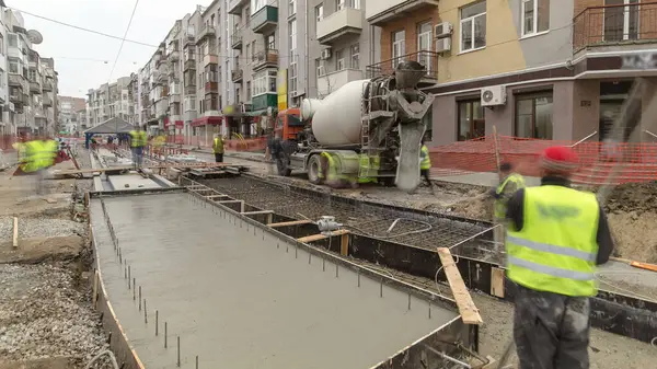 Beton döşeme, yol onarım şantiyesinde metal takviyesinde birçok işçi ve mikser zaman ayarlı olarak çalışır. Tramvay raylarının yeniden inşası
