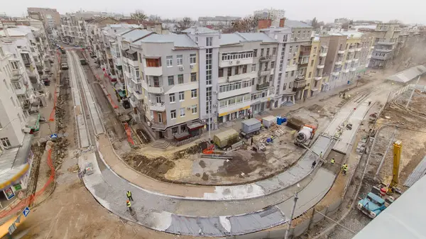 Beton yol yapımında çok sayıda işçi ve mikser makinesi, vinç, traktör zaman ayarlı çalışır. Tramvay raylarının yeniden inşası. Bulutlu bir günde hava üst görünümü