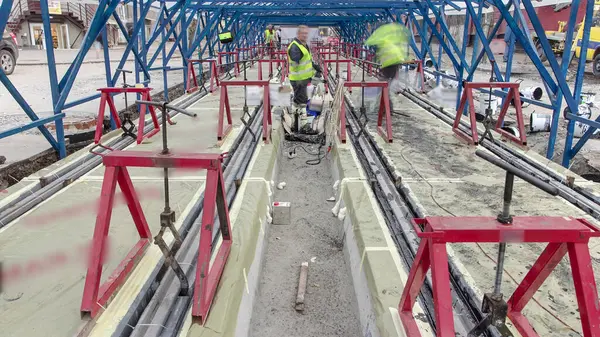 stock image Tram rails at the stage of their installation and integration into concrete plates on road. Workers make a mix of anti-vibration resin for rail comfort system. Process of reconstruction of tram tracks