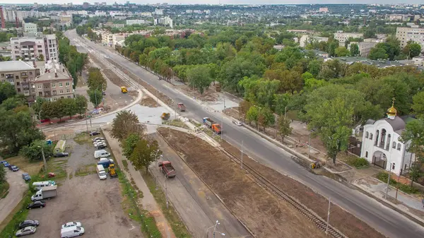 Büyük inşaat alanının panoramik hava görüntüsü. Buldozer, endüstriyel kamyon kazıcısı toprağı hareket ettiriyor ve bir çöp kamyonuna yüklüyor. Tramvay raylarının yeniden inşası