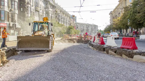 Buldozer hareket eder ve ezilmiş taş ve molozları zaman çizgisine yayar. Tramvay raylarının yeniden inşasında kazıcı olarak çalışıyorum. Yol yapım aşamasında. Havadan üst görünüm