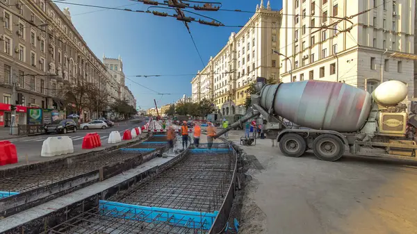 Yol inşaatı için metal takviyesi ve beton dökülüyor. Turuncu üniformalı ve mikser makineli bir sürü işçi var. Tramvay raylarının yeniden inşası
