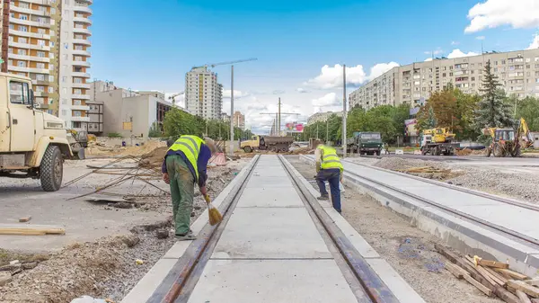 stock image Workers do cleaning of the railway tram line after construction works of modern railway rails for trams. Final stage of reconstruction of tram tracks