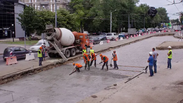 Tramvay rayları onarımı ve bakım zamanı olan bir yol inşaatı. Beton karıştırıcı ve birçok işçiyle kavşağın ortasında çalışır..