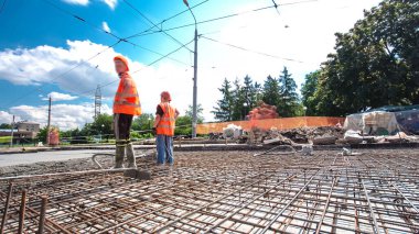 Tramvay rayları onarılan ve bakım süreleri yüksek olan yol inşaatı. Metal bir şebekede mikserden beton dökülüyor. Kavşağın ortası..