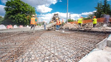 Tramvay rayları onarılan ve bakım süreleri yüksek olan yol inşaatı. Metal bir şebekeye beton dökülüyor. Kavşağın ortası..
