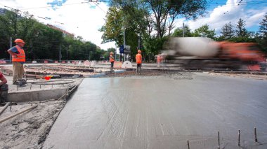 Tramvay rayları onarılan ve bakım süreleri yüksek olan yol inşaatı. Metal bir şebekeye taze beton dökülüyor. Kavşağın ortası..