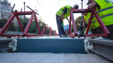Kurulum aşamasındaki tramvay rayları ve yoldaki beton plakalara entegrasyon. Titreşim ve gürültü için sıvı reçineyle doldurulmuş. Tramvay raylarının yeniden inşası