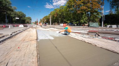 Beton yol yapım Tekdüzen timelapse işçi ile çalışır. Kaplama ve koruyucu filtre püskürtücü tarafından. Tramvay parça yeniden inşası