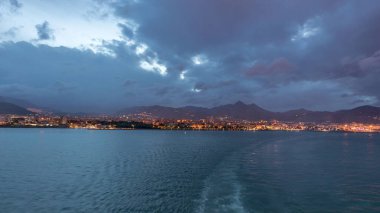 Gün batımından sonra açık denizde seyreden dalgalı ve limanlı deniz manzarası. Palermo kıyısı, İtalya