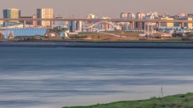 Lizbon 'daki Park Tejo ve River Timelapse' ın arka planında Milletler Bölgesi Modern Mimari Parkı var. Percurso Ribeirinho de Loures 'ten Vasco da Gama Köprüsü